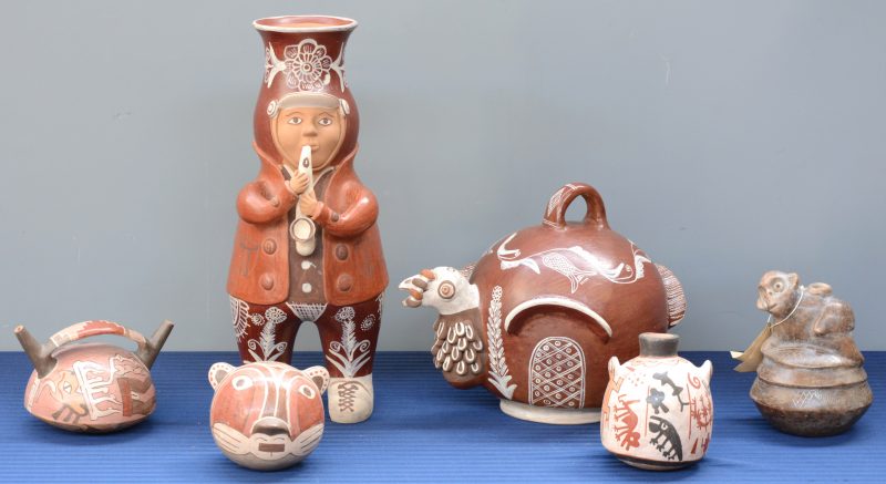 Een lot van zes stuks Peruviaans aardewerk w.o. een kruik in de vorm van een saxofoonspeler, een pot in de vorm van een kalkoen en vier kleinere.