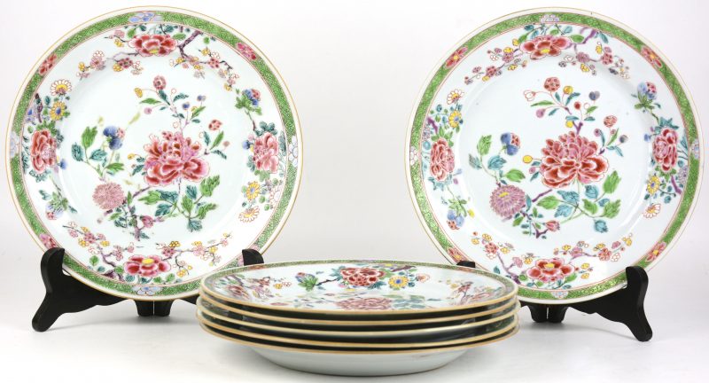 Een reeks van zeven borden van famille-roseporselein met een decor van bloesems en pioenrozen. 3 met haarscheurtjes.