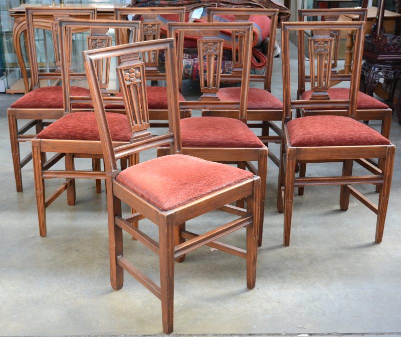 Een serie van acht notenhouten stoelen. Rechte poten, de ruggen versierd met een gesculpteerd bloemenmotief. Losse zitten met rode stof bekleed. XIXde eeuw.