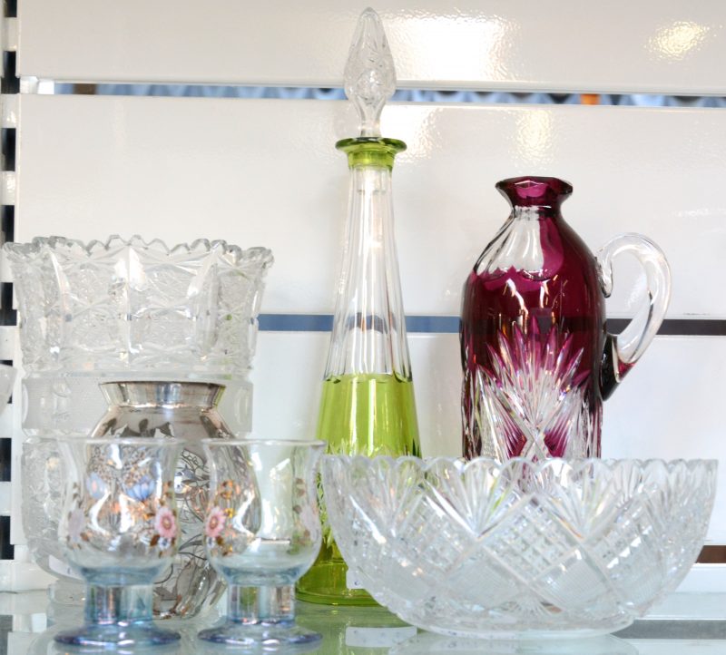 Een lot glaswerk en kristal, bestaande uit een vaas en een kom van kleurloos geslepen kristal, twee gekleurde karaffen, waarvan één zonder dop, een vaasje met een decor van zilververf en twee glaasjes met bloemenmotief.