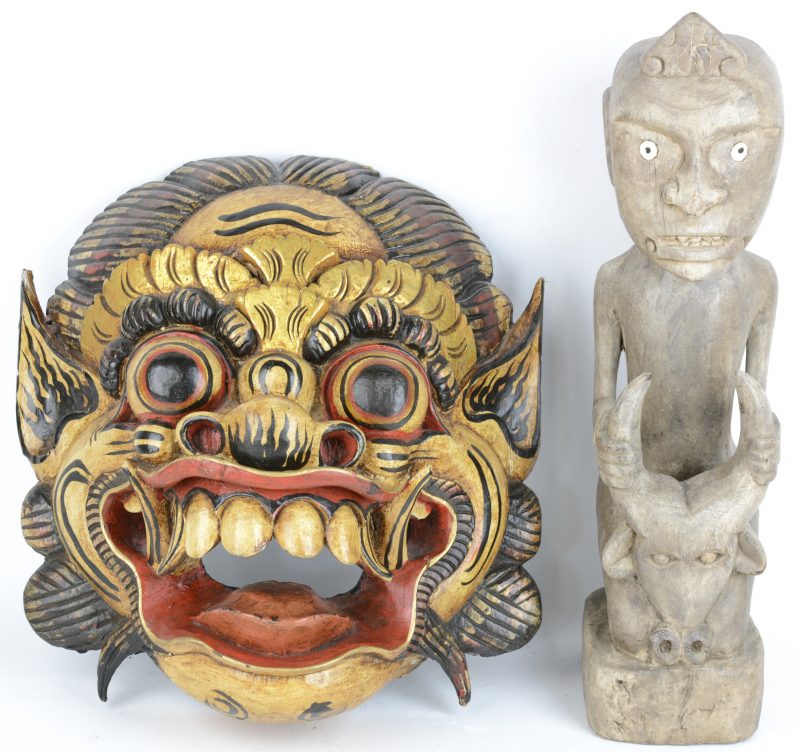 Een figuur met een stierenkop en een masker van gesculpteerd hout. Indonesië.