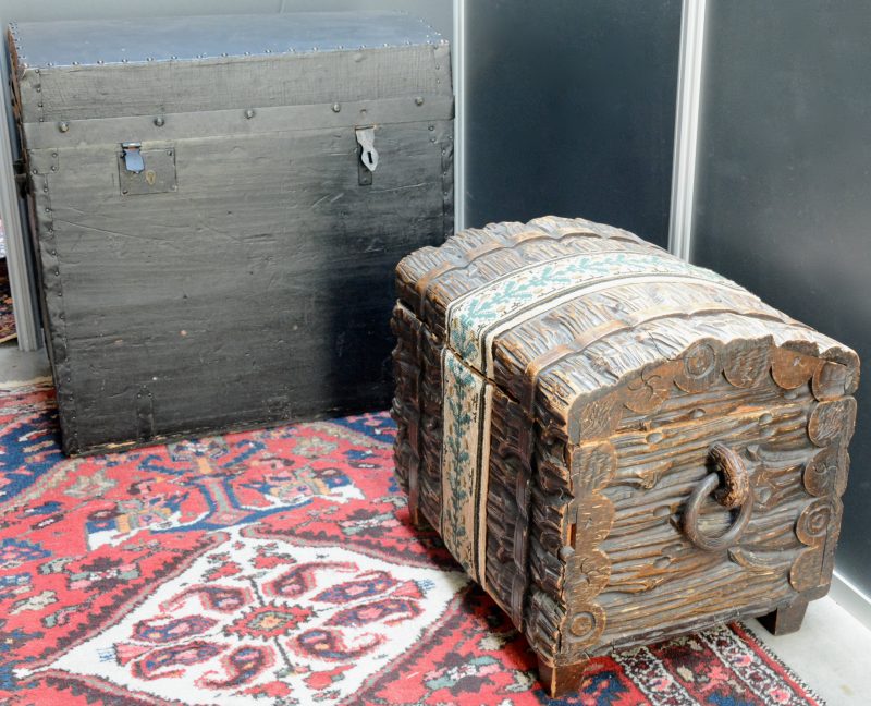 Een zwartgelakte houten koffer. We voegen er een tweede exemplaar van gesculpteerd hout aan toe.