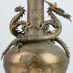 Een Chinese balustervaas van brons, gedecoreerd met een draak alangs de hals en een voorstelling in een cartouche op de buik. Onderaan gesigneerd.