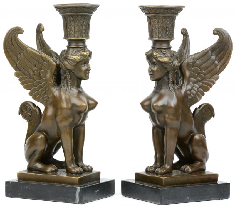 Een paar bronzen kandelaars in empirestijl in de vorm van zittende sfinxen op een marmeren sokkel.