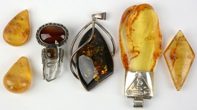 Drie hangers van amber, één met bergkristal gezet in zilver van 925‰. We voegen er nog drie hangers van amber aan toe.