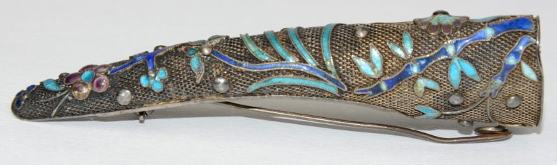 Een nagelbeschermer gemonteerd als broche van zilver bezet met email. 19de eeuws.