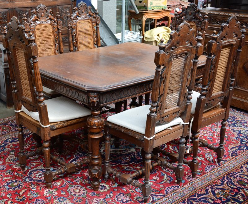 Een eikenhouten tafel met zes stoelen met gevlochten zit en rug in Mechelse Renaissancestijl.