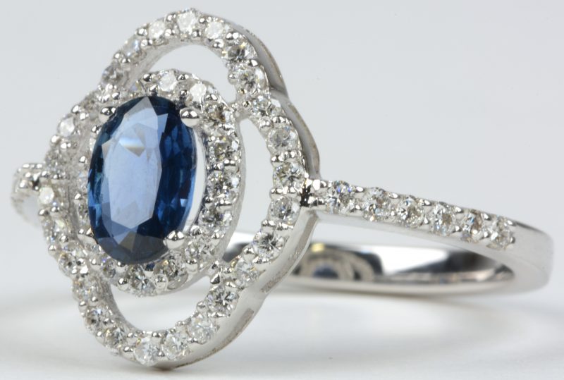 Een 18 karaats wit gouden ring bezet met diamanten met een gezamenlijk gewicht van ± 0,60 ct. en een saffier van ± 0,75 ct.