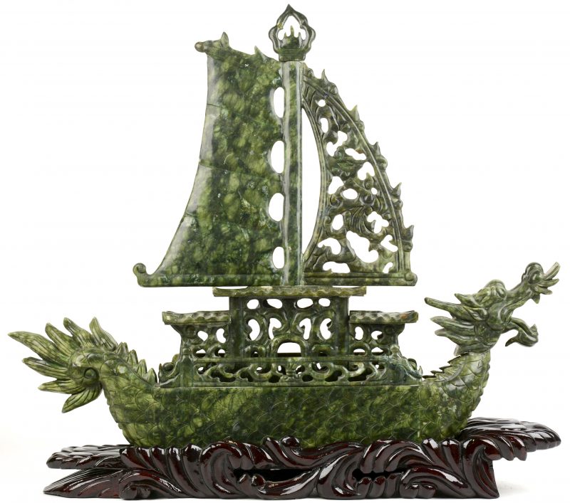 Een Chinees schip van gesculpteerd jade in de vorm van een draak op een sokkel van gesculpteerd hardhout.