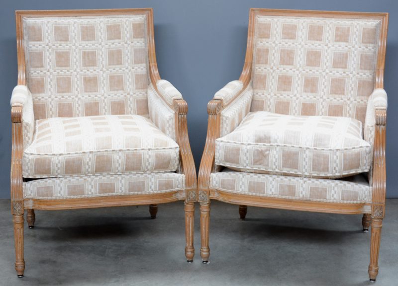 Een paar fauteuils van gebeitst eikenhout met stoffen bekleding in Lodewijk XVI-stijl.