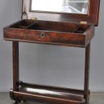 Een naaitafeltje van gefineerd mahoniehout met spiegel binnenin het klapblad. XIXde eeuw.