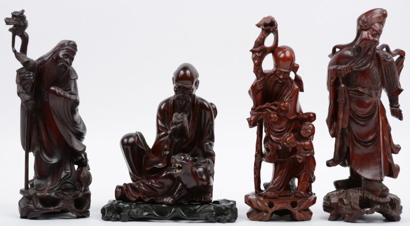 Een Chinese wijze met kind en perzikken, één met schaap, een lezende wijze met tijger en een krijgsheer van gesculpteerd hardhout.