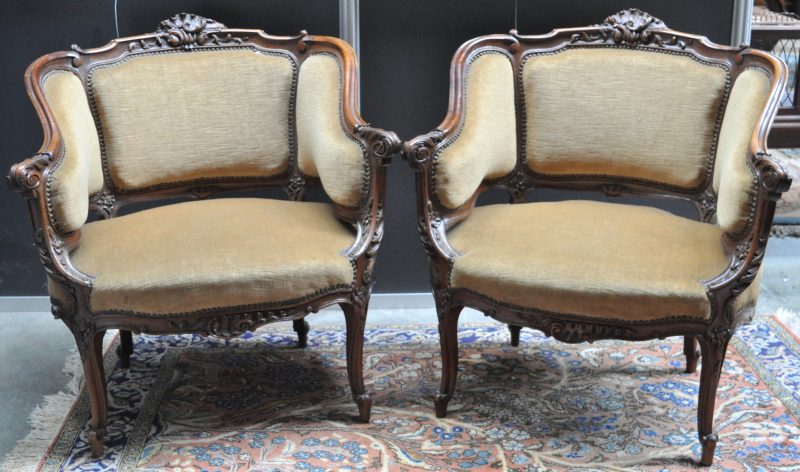 Een paar fauteuils van gesculpteerd eikenhout in Lodewijk XV-stijl, bekleed met fluweel.