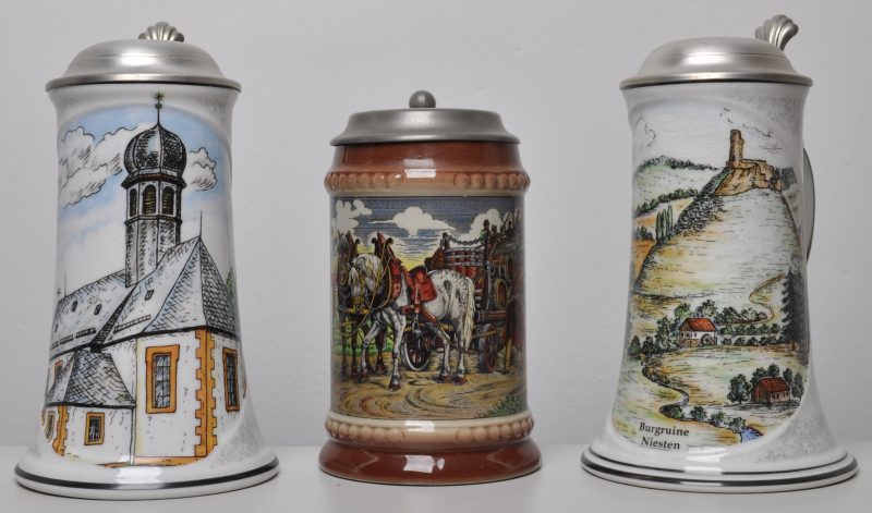 Drie bierpullen van porselein en aardewerk met tinnen deksels. Eén met een kapel en één met “Burgruine Niesten”, beide onderaan gemerkt Schedel, Bavaria. Eén met een bierkar.