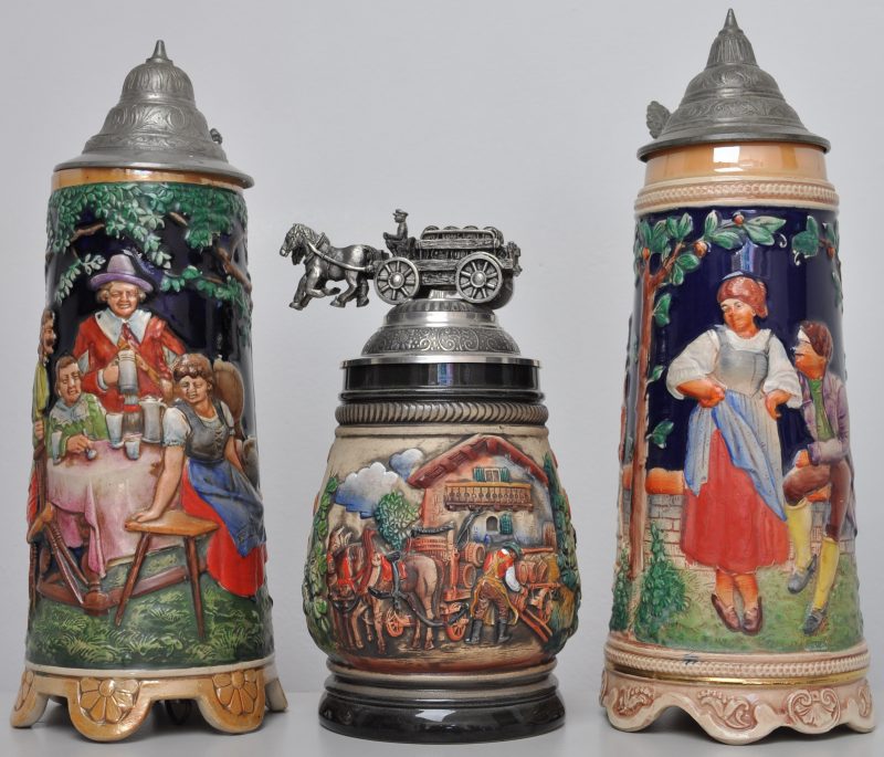 Drie bierpullen van aardewerk met tinnen deksels. Waarvan twee met muziek: één met een Biergarten (H. 29 cm) en één met een romantisch koppel (H. 30 cm). Eén met een brouwerijscène en met een bierkar op het deksel, gemerkt Zöller & Born (H. 21 cm).