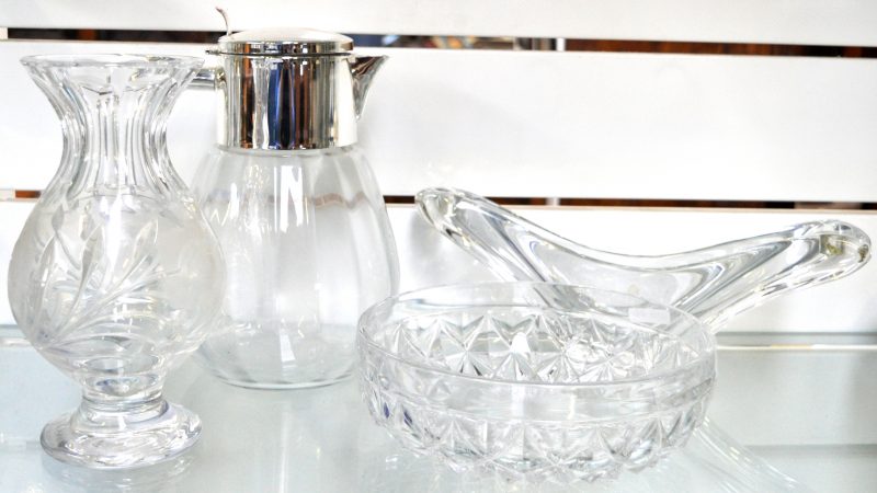 Een lot kleurloos kristal, bestaande uit een dubbele kandelaar en een vaas op voet met een geslepen bloemendecor, een waterkan met verzilverde montuur en een geslepen schaal.