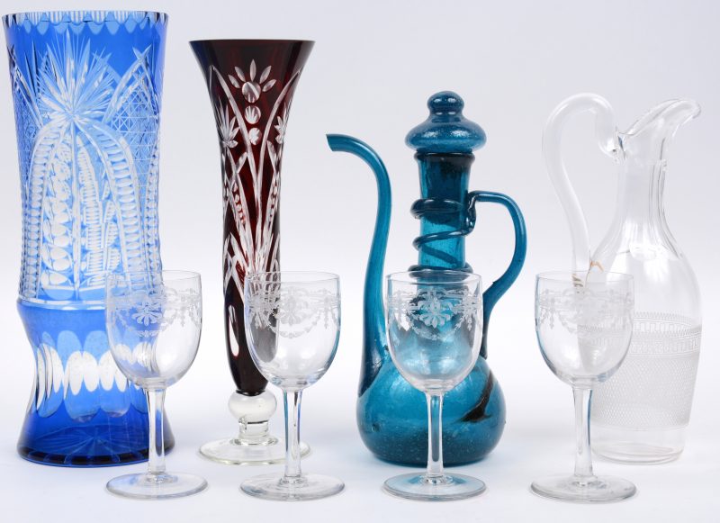 Een lot glas en kristal, bestaande uit een bruinrode en een blauwe vaas van kristal, een kleurloos karafje met vier glaasjes en een blauw glazen karafje.