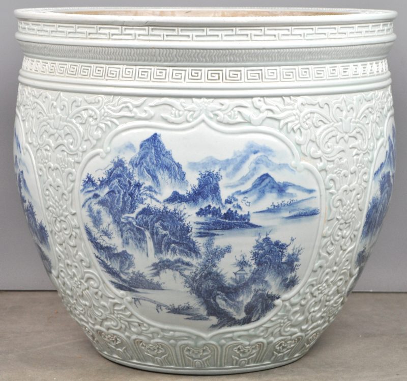Een grote porseleinen cachepot met blauwe landschapsdecors in cartouches. Chinees werk.