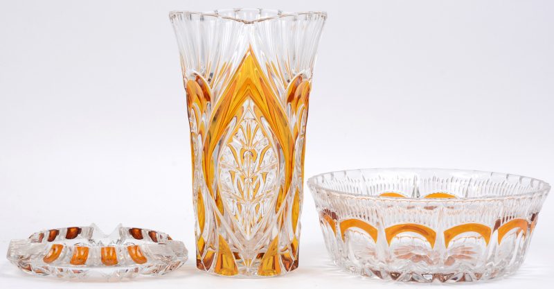 Een lot kristal met amberkleurige accenten, bestaande uit een asbak, een vaas en een coupe.