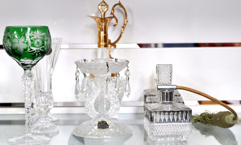 Een lot kristal, bestaande uit een driedelig toiletstel, een kannetje met koperen monturen, een kandelaar met pendeloques, een vaasje op voet, een groen wijnglas en een solifiore.