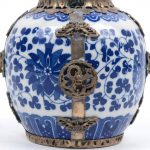 Een theepotje van Chinees porselein met een met een blauw op wit gedrukt bloemendecor en versierd met wit metalen monturen met mythologische dieren. Onderaan gemerkt.