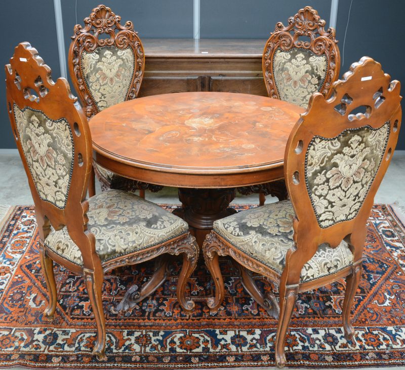 Ronde tafel met centrale poot en vier bijpassende stoelen met uitgewerkte ruggen. Barokke stijl. Tafelblad met slijtageplekken.