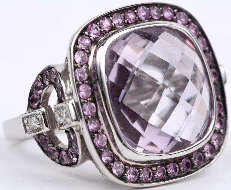 Een 18 karaats wit gouden ring bezet met diamanten met een gezamenlijk gewicht van ± 0,15 ct. een grote en kleine roze saffieren en amethist met een gezamenlijk gewicht van ± 14 ct.