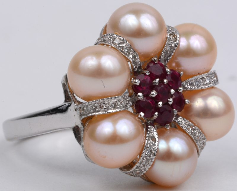 Een 18 karaats wit gouden ring bezet met diamanten met een gezamenlijk gewicht van ± 0,12 ct., robijnen met een gezamenlijk gewicht van ± 0,90 ct. en zes parels.