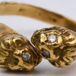 Een 18 karaats geel gouden ring in de vorm van leeuwenkopjes bezet met vier briljantjes.