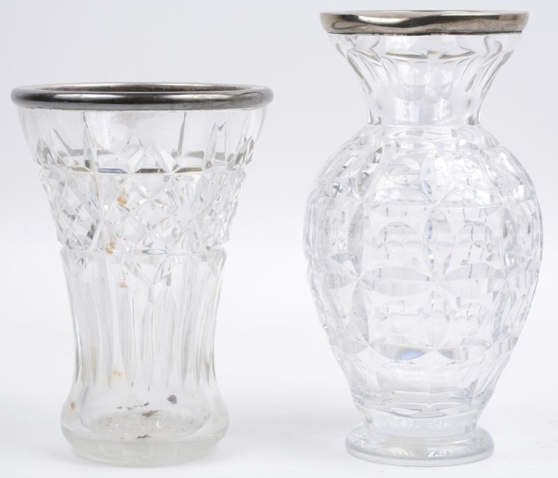 Twee verschillende vazen van geslepen kleurloos kristal met zilveren monturen van Wolfers, resp. 833 en 925‰.