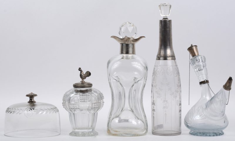 Een lot glaswerk, bestaande uit een karaf, een azijnkan, een dekselvaasje met een haan (Schilfer onderaan), een fles en een stolp. Allen met zilveren monturen, de laatste verzilverd.