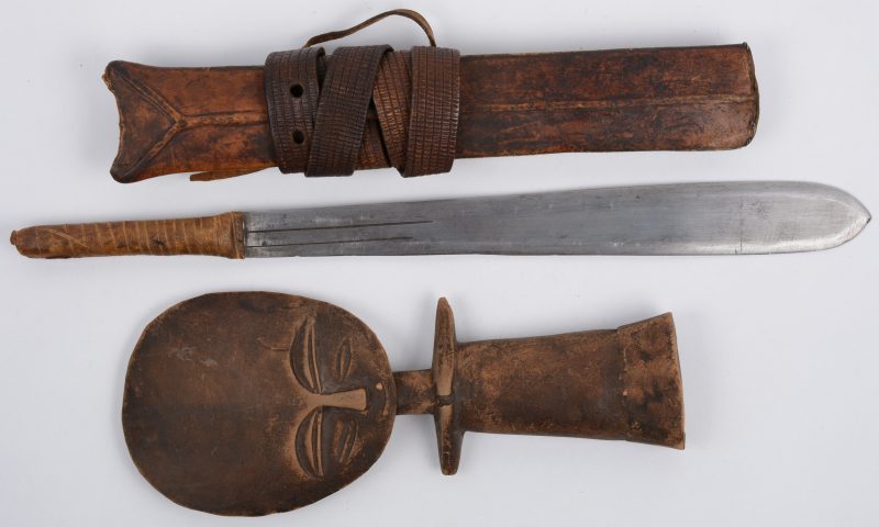 Een Afrikaans beeldje en een mes met lederen handvat en schede.