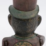 Een gietijzeren spaarpot in de vorm van een bediende met hoge hoed.