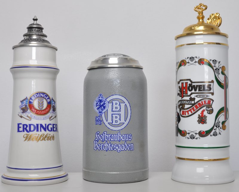 Drie bierpullen van steengoed en porselein met tinnen deksels. Eén met reclame voor Erdinger Weissbier, gemerkt PJW Bavaria, één voor Hofbrauhaus Berchtesgaden en één voor Hövels Bitterbier, gemerkt Sahm.
