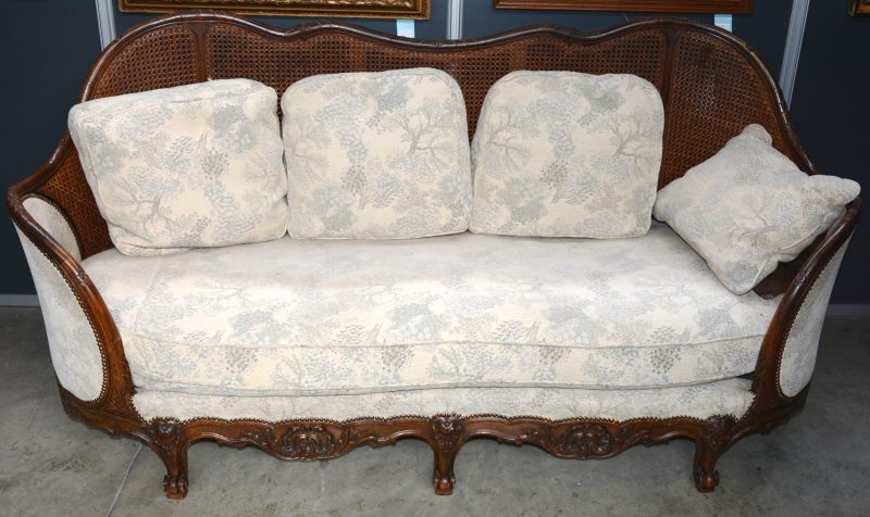 Een sofa van gesculpteerd eikenhout met gecanneerde rug.