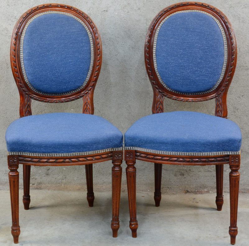 Een paar stoelen van gesculpteerd notenhout in Lodewijk XVI-stijl, bekleed met blauw fluweel.