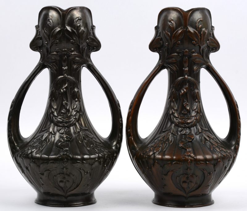 Een paar siervazen van donkergepatineerd brons, versierd met guirlandes.