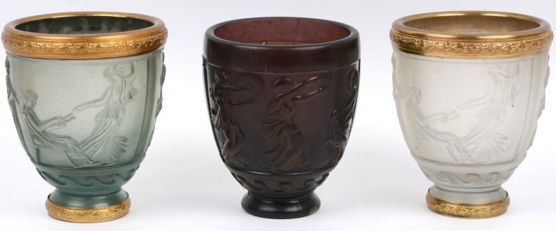 Drie vazen van gegoten en gesatineerd glas, versierd met Griekse taferelen in bas-reliëf en waarvan twee met messingen monturen.