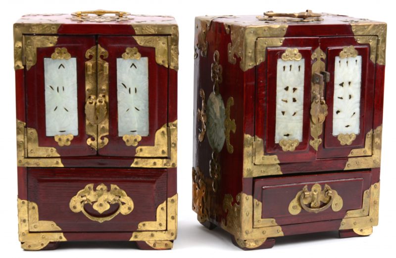Een paar Chinese juwelenkabinetjes van roodgelakt hout met messingen monturen en jade plaquettes.