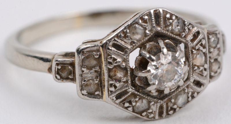 Een 18 karaats wit gouden ring bezet met één centrale briljant van ± 0,20 ct. en kleine diamantjes oude slijp.