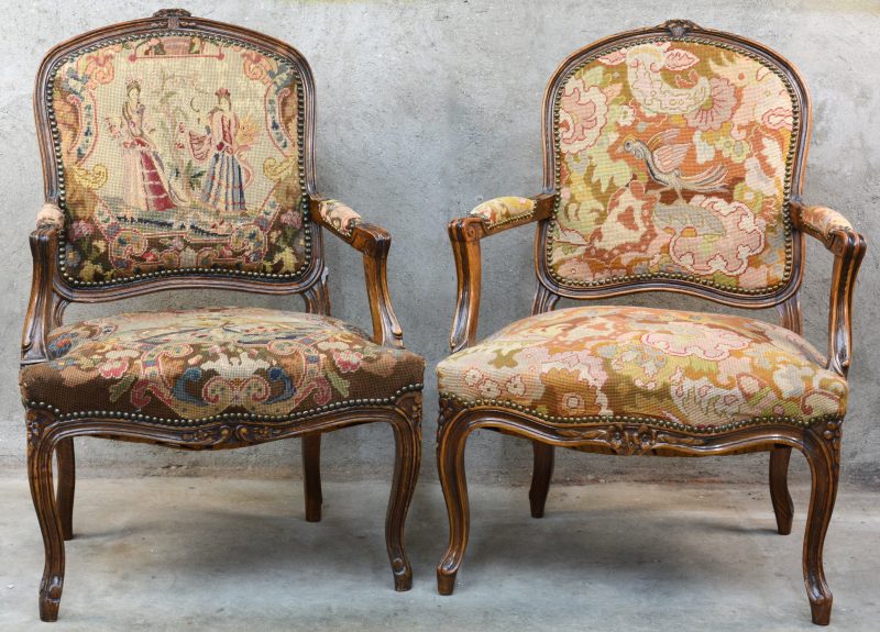 Twee fauteuils à la reine van gesculpteerd eikenhout, waarbij één versierd met naaldwerk en de andere met tapisserie.