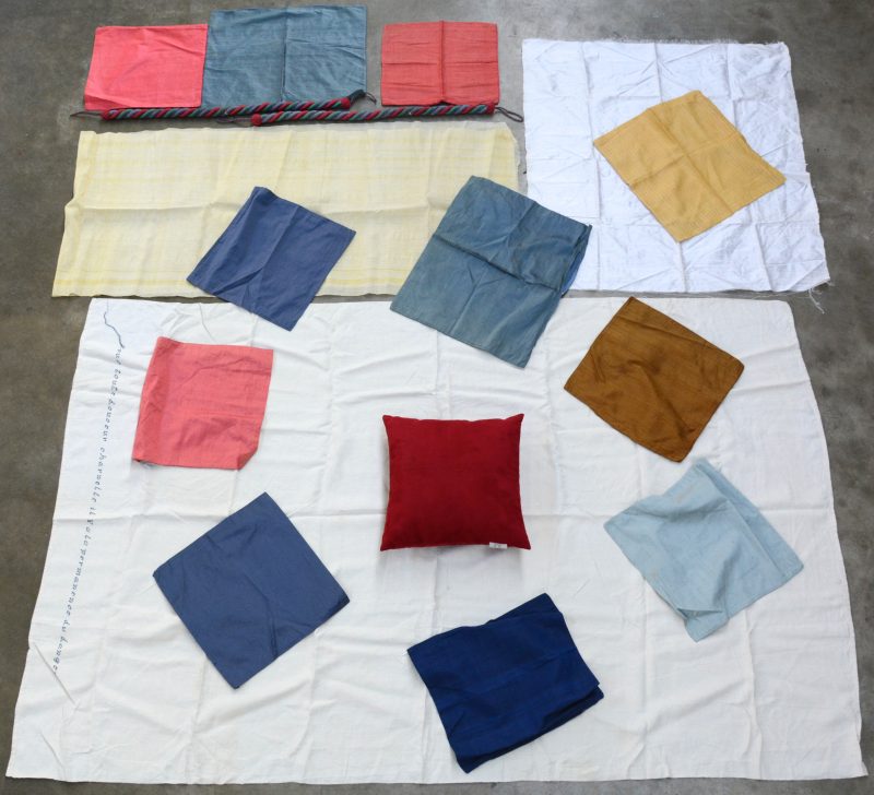 Een lot textiel bestaande uit 11 kussenslopen van zuiver zijde, een kussen van rood fluweel, twee stroken zijde, een kleurig gordijnkoord en een lap linnen van ongeveer 200 x 100 cm met een geborduurde tekst.