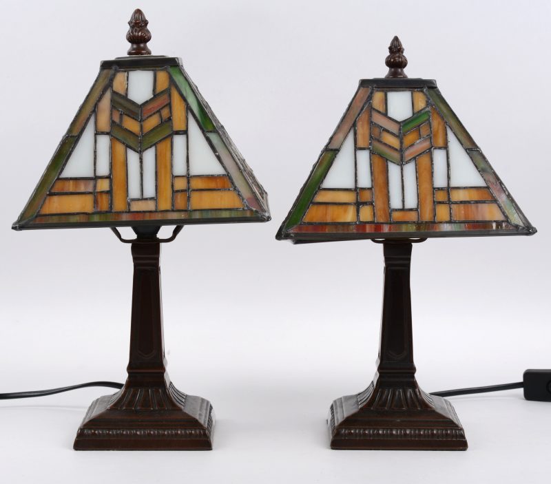 Een paar tafellampjes van bruingepatineerd zamak met glazen kapjes in de geest van Tiffany’s.