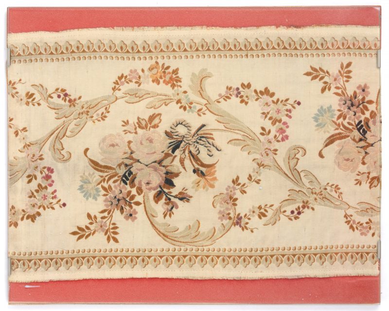 Een ingelijste strook zijde met bloemenmotief. Tijdperk Lodewijk XVI.