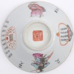 Een kopje van polychroom Chinees porselein versierd met personages en kalligrafie. Kleine schilfer.