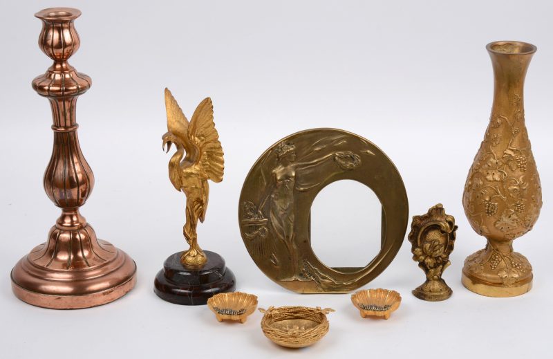 Een lot koper en brons, bestaande uit een vaasje met een druivendecor, een art nouveau fotokader, een kandelaar, een rocaille, twee schelpjes, een vogelnestje en een beeldje in de vorm van een reiger.