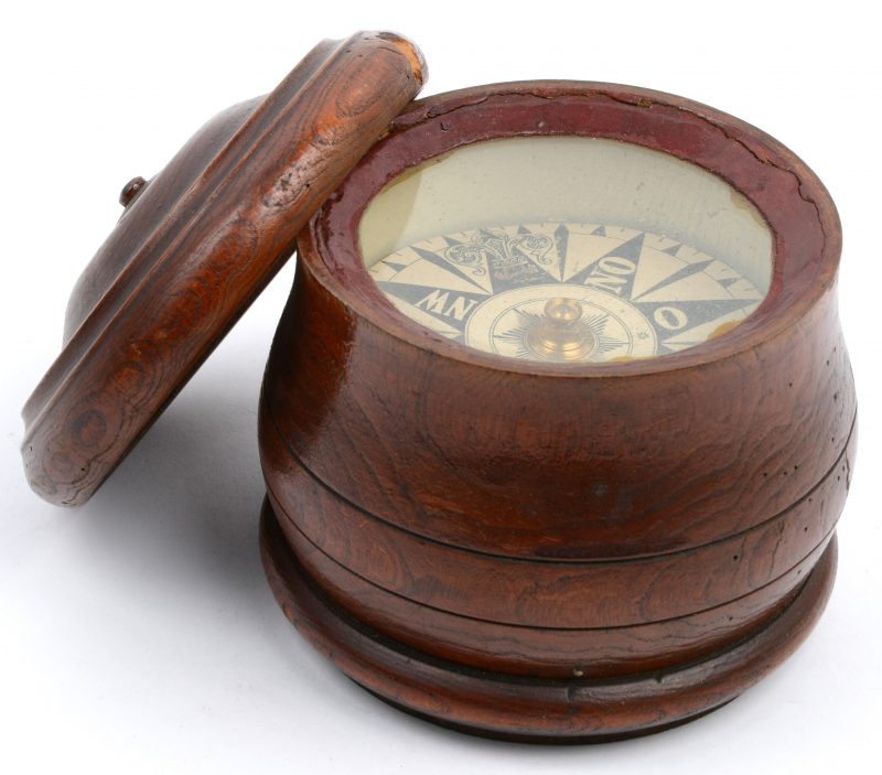 Een oud kompas in een gedraaide houten houder met deksel.