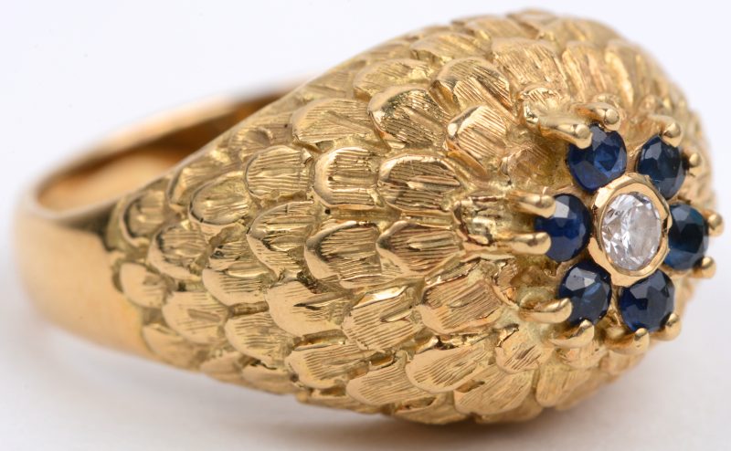 Een 18 karaats geel gouden ring bezet met één centrale diamant van ± 0,10 ct. en saffieren  met een gezamenlijk gewicht van ± 0,20 ct.