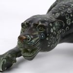 Een bronzen beeld van een sluipende jaguar.