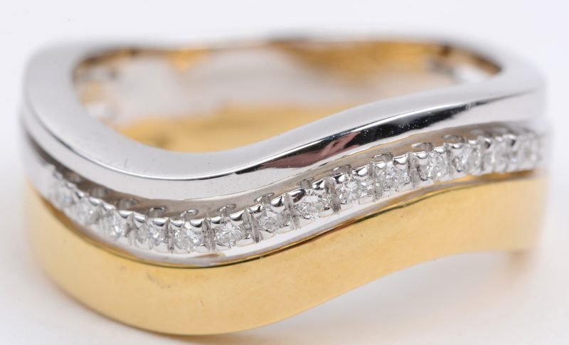 Een 18 karaats wit en geel gouden ring bezet met diamanten met een gezamenlijk gewicht van ± 0,12 ct.